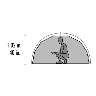 Eine Person sitzt mit gekreuzten Beinen in einem MSR® Elixir™ 2 „V2“ Backpacking-Zelt mit einer Höhe von 1,02 Metern oder 40 Zoll, das für 2 Personen ausgelegt ist.