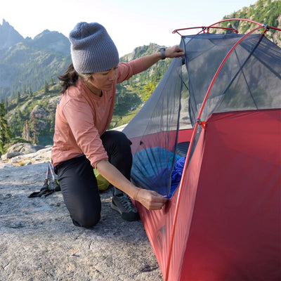 Eine Person richtet ein ultraleichtes MSR® FreeLite™ 1 „V2“ 1-Personen-Backpacking-Zelt in einer bergigen Outdoor-Umgebung auf.