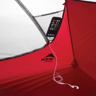 Smartphone und Kopfhörer in einem roten MSR® FreeLite™ 1 „V2“ Ultraleichtes 1-Personen-Backpacking-Zelt mit Teilblick auf das Zeltinnere und Reißverschluss