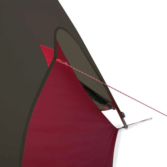 Eine Nahaufnahme eines rot-schwarzen MSR® FreeLite™ 1 „V2“ Ultraleichtes 1-Personen-Backpacking-Zelt, dessen eine Ecke mit einem Metallpflock und einer roten Abspannleine am Boden befestigt ist