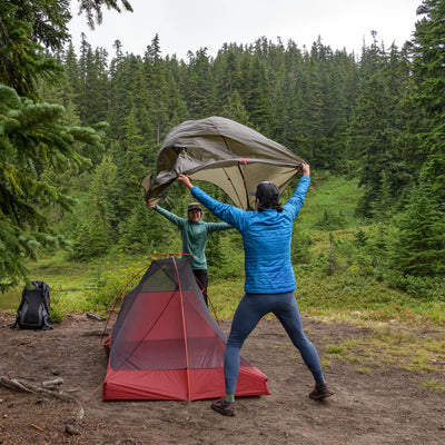 Zwei Personen richten ein ultraleichtes MSR® FreeLite™ 1 „V2“ 1-Personen-Backpacking-Zelt in einer Waldlichtung auf.