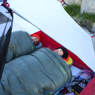Zwei Personen ruhen in Schlafsäcken auf einer Therm-a-Rest® NeoAir® XTherm™ NXT MAX Isomatte in einem Zelt.