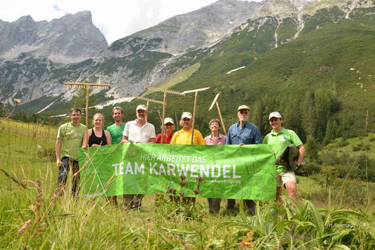 Gruppe Menschen mit Banner, Berge im Hintergrund, Naturschutzgebiet Karwendel, Teamfoto.