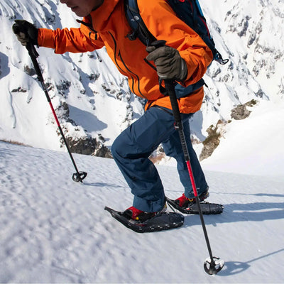 Ein Wanderer überquert mit Schneeschuhen und MSR® DynaLock™ Ascent Carbon Backcountry-Stöcken einen schneebedeckten Hang.