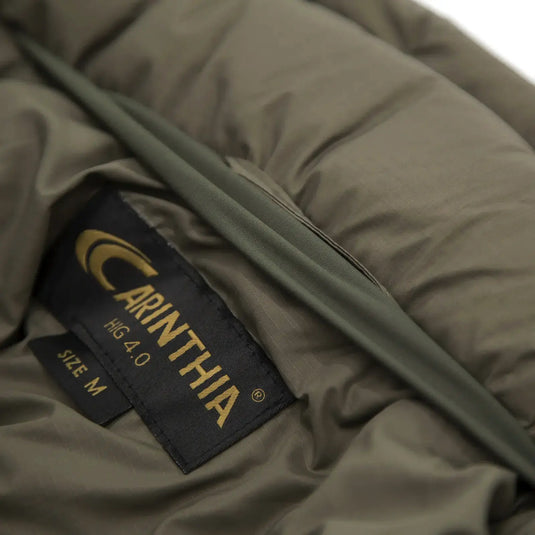 Nahaufnahme eines Markenetiketts der Carinthia® HIG 4.0 Jacke auf olivgrünem Stoff, Outdoor-Kleidung oder Ausrüstung.