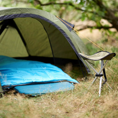 Ein Grand Canyon® Hattan 5.0 Campingzelt mit Schlafmatte und Klappstuhl, aufgebaut in einer natürlichen Umgebung im Freien.