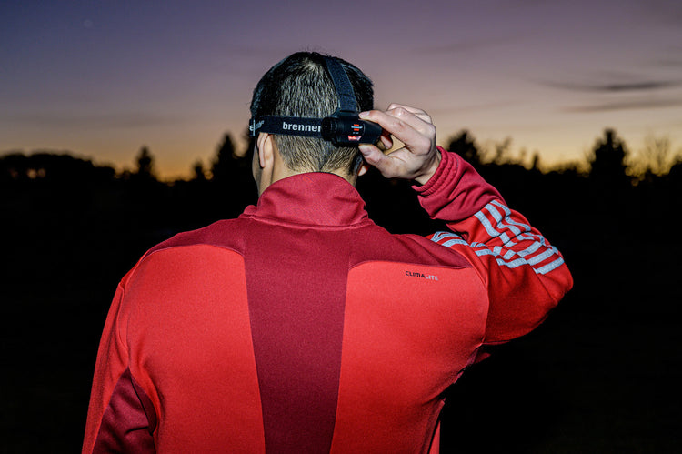 Person in roter Jacke stellt in der Abenddämmerung einen Scheinwerfer ein.