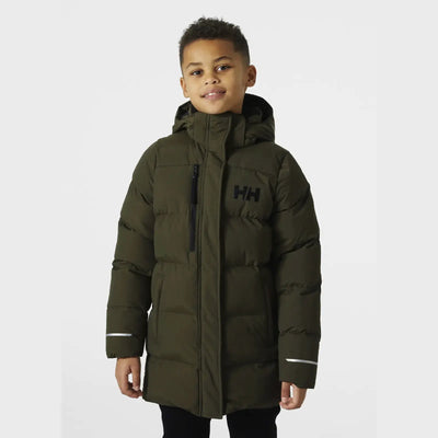 Kleiner Junge modelliert einen grünen Adore Puffy Parka von Helly Hansen® Juniors.