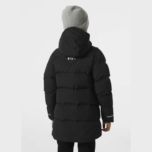 Person, die einen schwarzen Adore Puffy Parka von Helly Hansen® Juniors und eine graue Mütze trägt, von hinten.