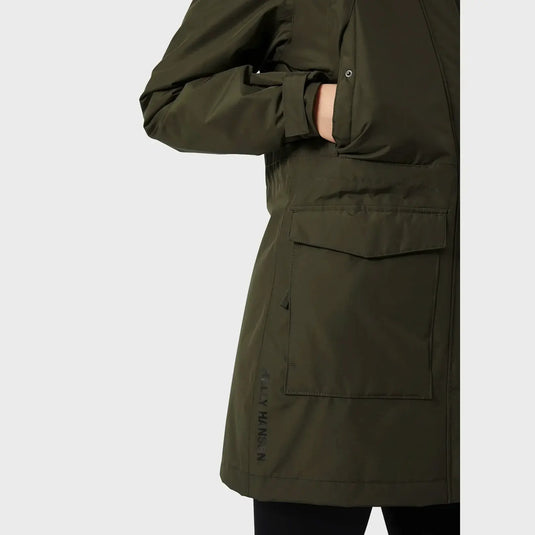 Person in einem grünen Frida-Winterparka für Damen von Helly Hansen® mit Hand in der Tasche, Seitenansicht.