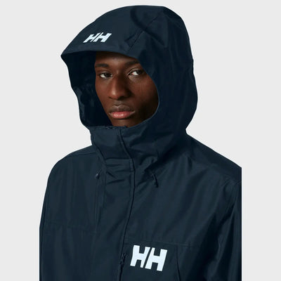 Person, die einen isolierten Helly Hansen® Men’s Rigging Insulated Raincoat mit dem Logo „hh“ auf der Brust trägt.