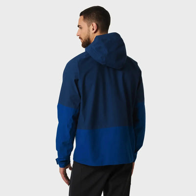 Mann trägt eine zweifarbige blaue Helly Hansen® Herren-Banff-Shelljacke mit hochgezogener Kapuze, von hinten gesehen.