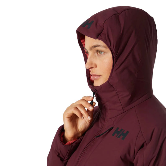 Frau in einer Helly Hansen® Women's Odin Stretch Hood Insulator 2.0-Jacke mit Reißverschluss vorne.