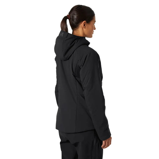 Frau trägt eine schwarze Helly Hansen® Women's Odin Stretch Hood insulator 2.0 Kapuzenjacke aus der Seitenansicht.