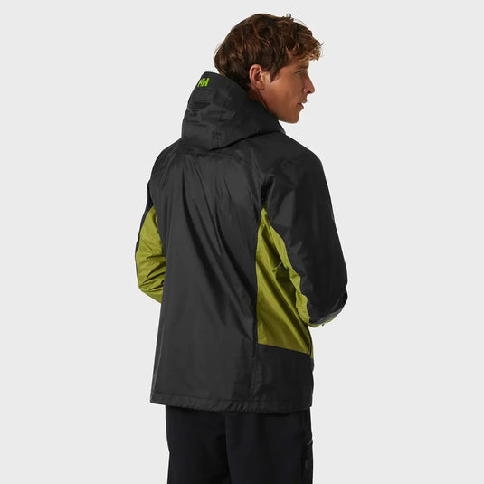 Eine Person von hinten gesehen, die eine schwarz-grüne Verglas 2L Shell-Jacke für Herren von Helly Hansen® mit einem sichtbaren Helly Hansen-Logo auf der Kapuze trägt.