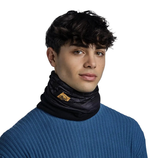 Junger Mann mit lockigem Haar, trägt einen blauen Pullover und einen Buff® für Wärme und Nachhaltigkeit.