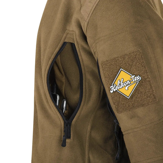 Helikon-Tex® Liberty-Jacke – Doppelfleece mit einer teilweise geöffneten Tasche, in der sich ein Stift befindet, und einem „Helikon-Tex“-Aufnäher am Ärmel.