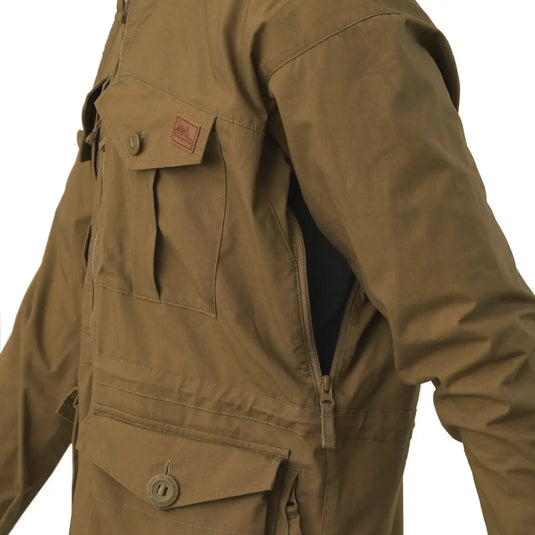 Nahaufnahme einer Person, die eine grüne Helikon-Tex® SAS Smock-Jacke mit Taschen und Reißverschluss trägt.