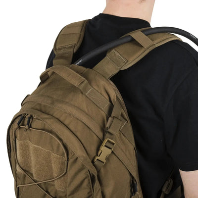 Person, die einen braunen Helikon-Tex® EDC-Rucksack – Cordura (21 Liter) über einer Schulter trägt.