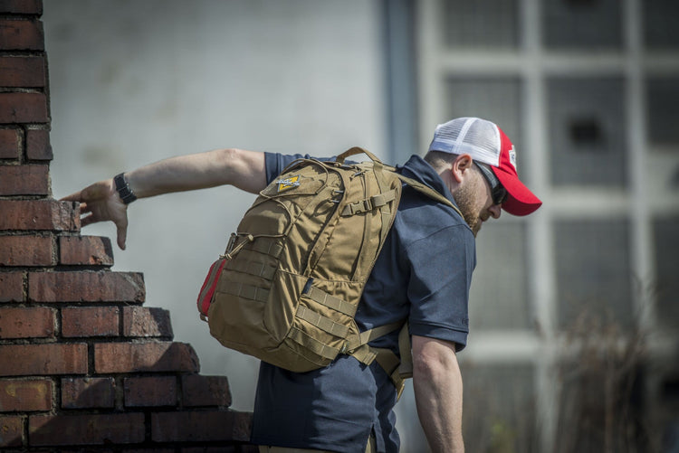 Mann mit Rucksack streckt sein Bein aus, als würde er über eine niedrige Barriere steigen.