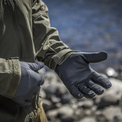 Eine Person, die Helikon-Tex® Impact Duty Winter MK2-Handschuhe mit rutschfestem Material trägt, streckt eine offene Hand ins Freie.