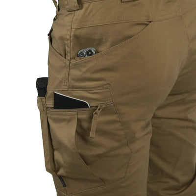 Nahaufnahme einer Person, die Helikon-Tex® Urban Tactical Pants aus khakifarbenem Polycotton-Ripstop trägt und ein Smartphone in der Seitentasche hat.