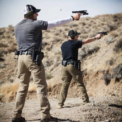 Zwei Personen trainieren im Freien mit Schusswaffen und tragen Helikon-Tex® Urban Tactical Pants – Polycotton Ripstop.