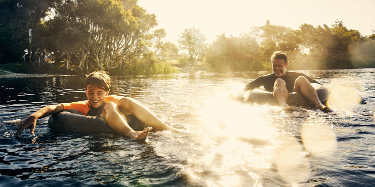 Zwei Menschen genießen einen sonnigen Tag, während sie auf einem ruhigen Fluss treiben.