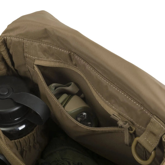 Nahaufnahme einer offenen braunen Helikon-Tex® Bushcraft Haversack Bag – Cordura, mit einer Wasserflasche und anderer Ausrüstung darin.