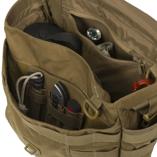 Offene Helikon-Tex® olivgrüne Cordura Bushcraft-Rucksacktasche mit verschiedenen Gegenständen, darunter Kopfhörer, eine Flasche und elektronische Geräte.