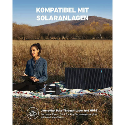 Frau sitzt draußen mit einer ANKER Powerstation 256Wh | 200 W, eine mobile Energiequelle, die mit Solarenergiesystemen kompatibel ist.