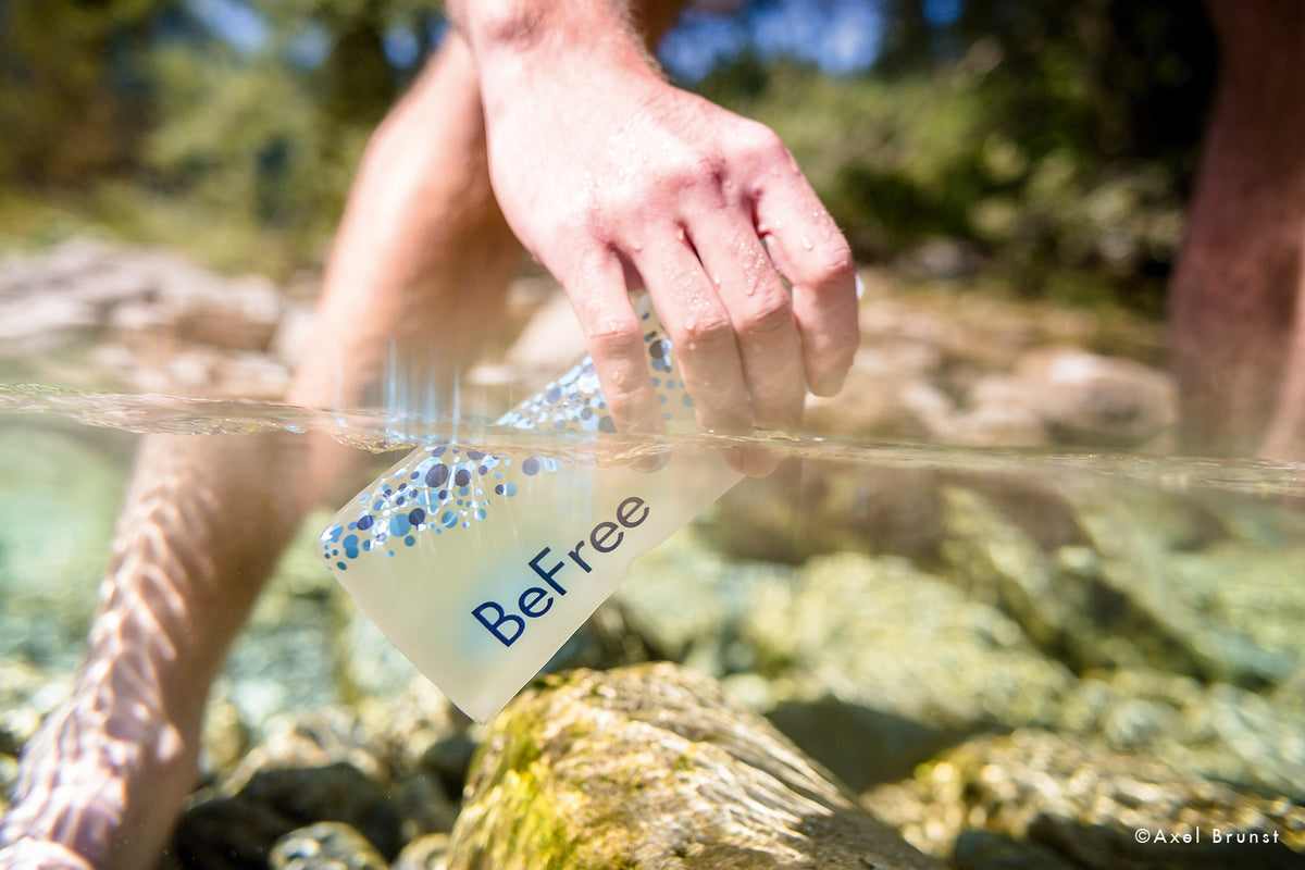 Eine Hand hebt eine wasserdichte Karte aus einem klaren Fluss.