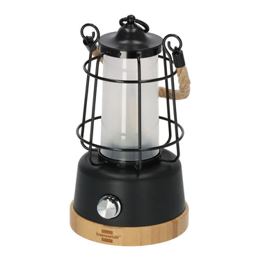 Brennenstuhl® Akku-Campinglampe „CAL 1“ mit schwarzem Oberteil, klarem Zentralrohr, schützendem Metallkäfig und einem Holzsockel mit dimmbarem Bedienknopf.