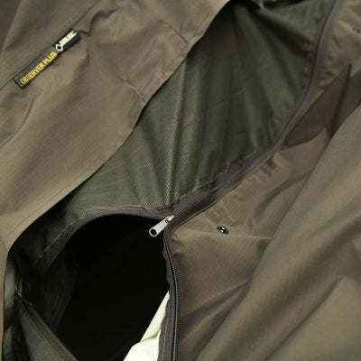 Nahaufnahme einer olivgrünen Carinthia® OBSERVER PLUS-Jacke mit teilweise geöffnetem Reißverschluss vorne.