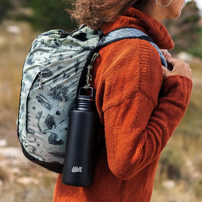 Frau mit gemustertem Rucksack und einer Esbit® Trinkflasche Sculptor 1000ml Edelstahl steht im Freien.