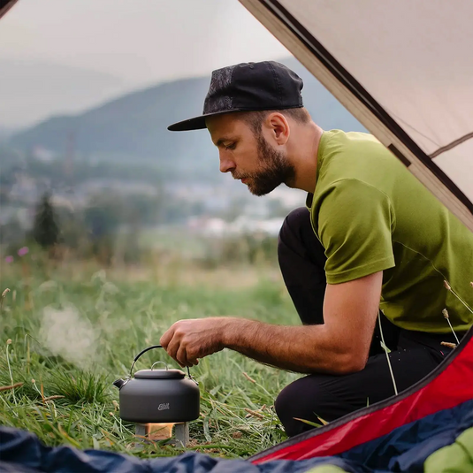 Mann bereitet beim Camping eine Mahlzeit auf einem tragbaren Esbit®-Aluminiumkocher zu.