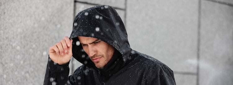 Ein Mann mit Kapuze trotzt einem Schneefall.