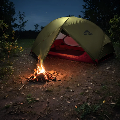 Ein MSR® Hubba Hubba™ NX V7, 2-Personen-Ultraleichtes-Backpacking-Zelt neben einem Lagerfeuer unter einem Nachthimmel.