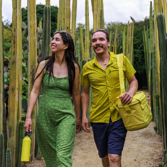 Paar geht Hand in Hand durch einen Kaktusgarten, jeder trägt einen Hydro Flask® Carry Out™ Soft Cooler / Kühltasche.