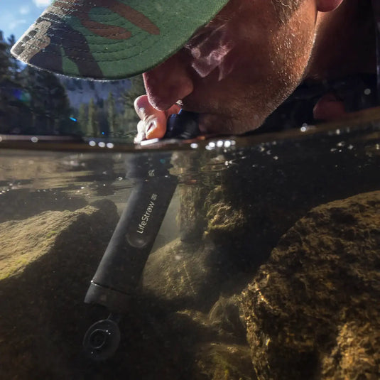 Eine Person nippt an Trinkwasser durch einen LifeStraw® Peak Series Strohhalm aus einer natürlichen Wasserquelle.