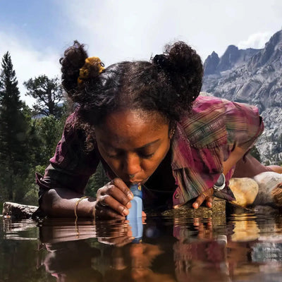 Eine Frau trinkt mit einem Strohhalm der LifeStraw® Peak-Serie aus einem Bergsee.