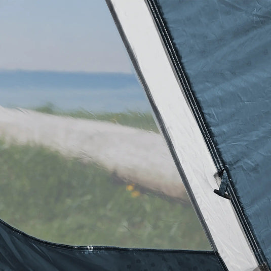 Eine teilweise geöffnete Outwell®-Zeltklappe zeigt eine verschwommene Naturlandschaft mit Wasser und Wolken im Hintergrund.