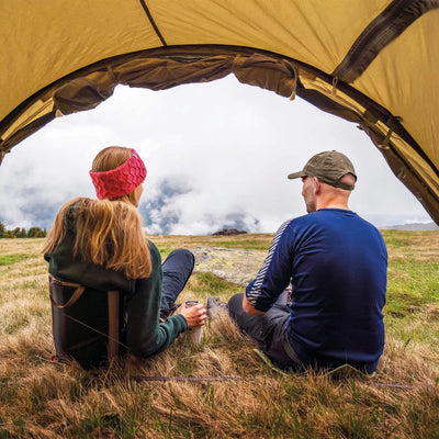 Zwei Personen sitzen am Robens® 3-Personen Zelt Voyager Versa 3 Eingang, genießen Sie ein Outdoor-Erlebnis mit Bergblick.