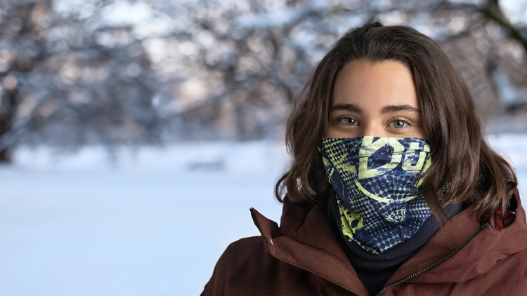 Eine Person mit einer bunten Maske in einer winterlichen Umgebung.