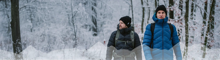 Zwei Menschen wandern in einem verschneiten Wald.